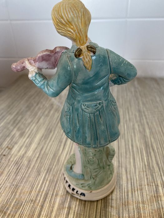 Estátua em cerâmica de um homem que segura um violino