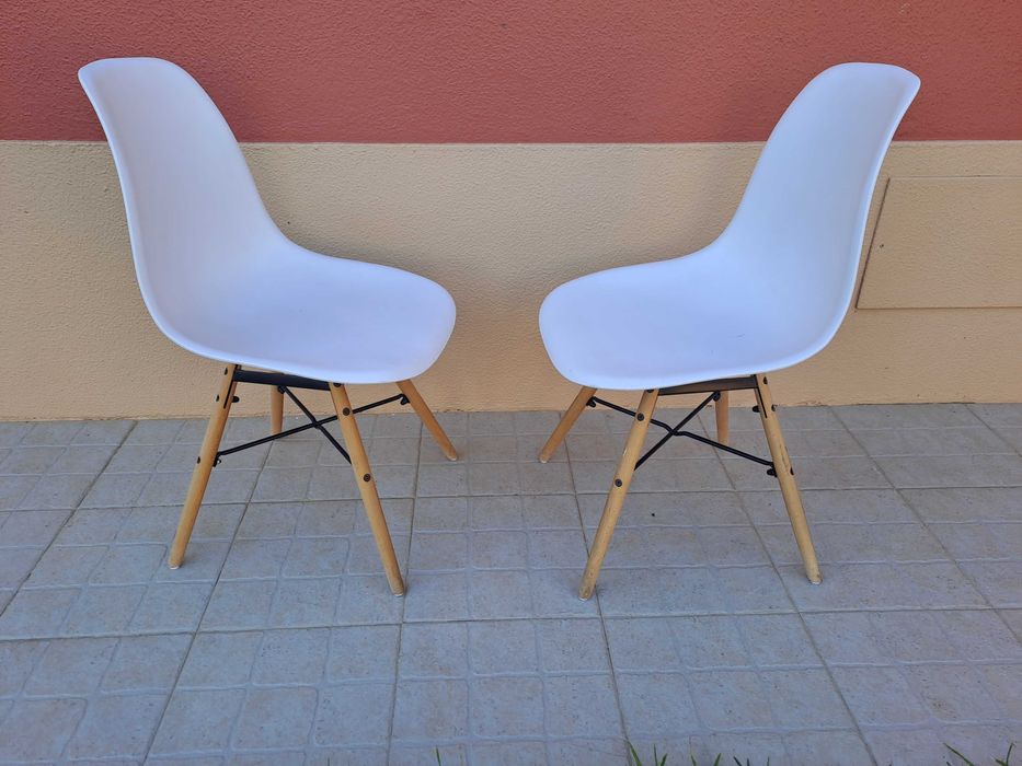 Cadeiras brancas e pernas de madeira.