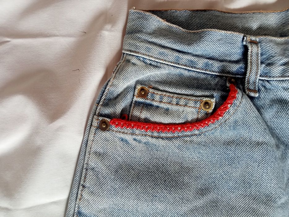 Calções curtos e rotos á frente com um pequeno debruado nas algibeiras