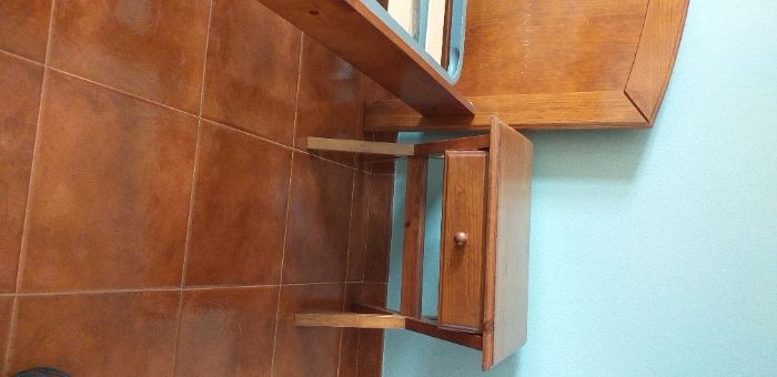 Cama de solteiro com estrado e mesa de cabeceira.