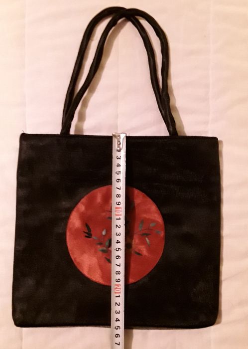 Bolsa ou mala de mão preta com aplicação circular vermelha