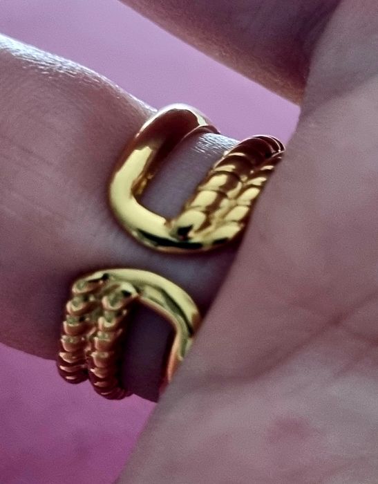 Anel dourado, em aço, com uma  madrepérola  oval no centro. Ajustável