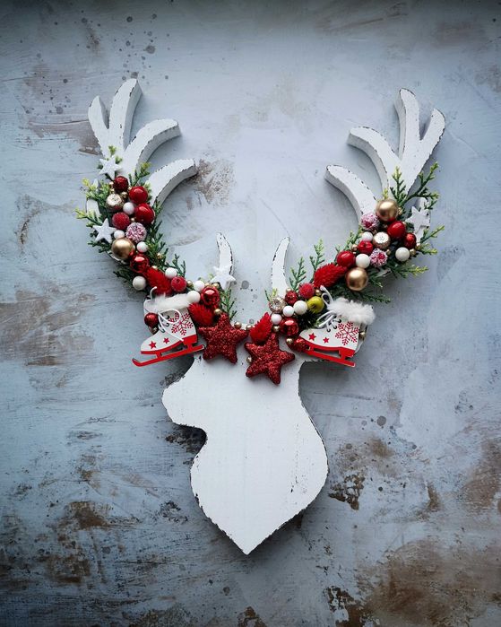 Drewniana głowa renifera z ozdobami i zielonymi gałązkami święta