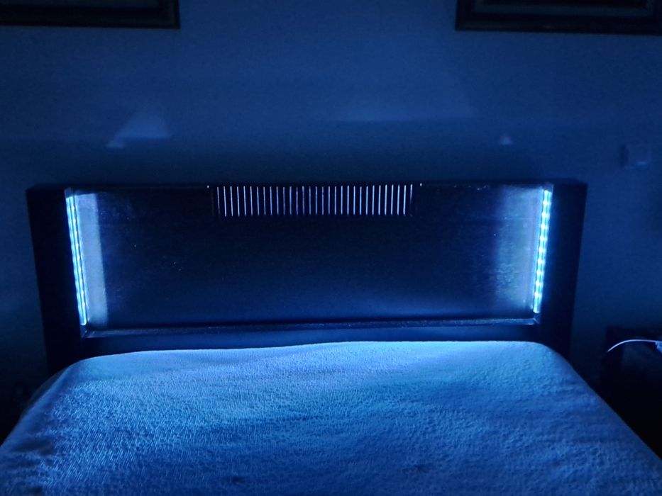 Cama de casal,  cor castanho escuro, com iluminação.