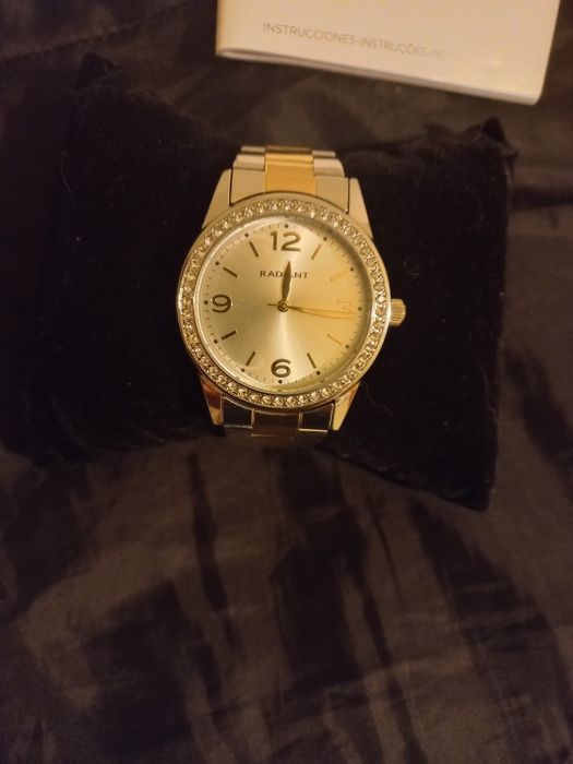 Relógio prateado e dourado com zirconias à volta do mostrador.