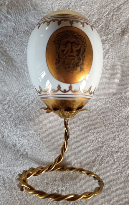 Ovo de Páscoa de porcelana com decorações douradas.Assente num suporte