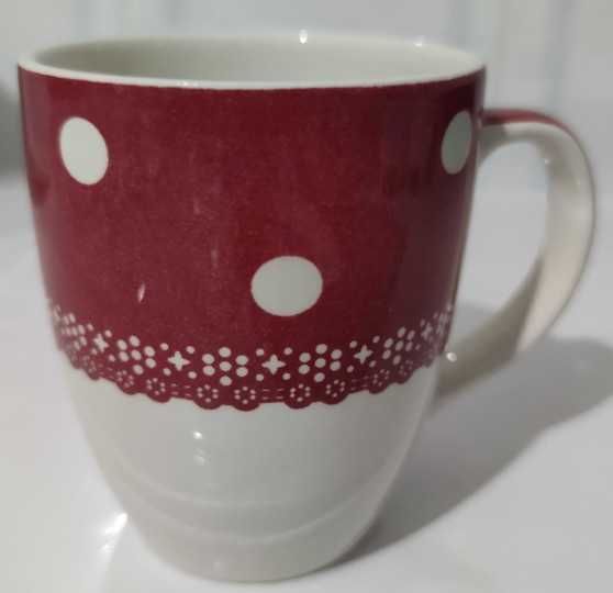 Caneca de cerâmica com um padrão de bolinhas e flores brancas sobre um fundo vermelho