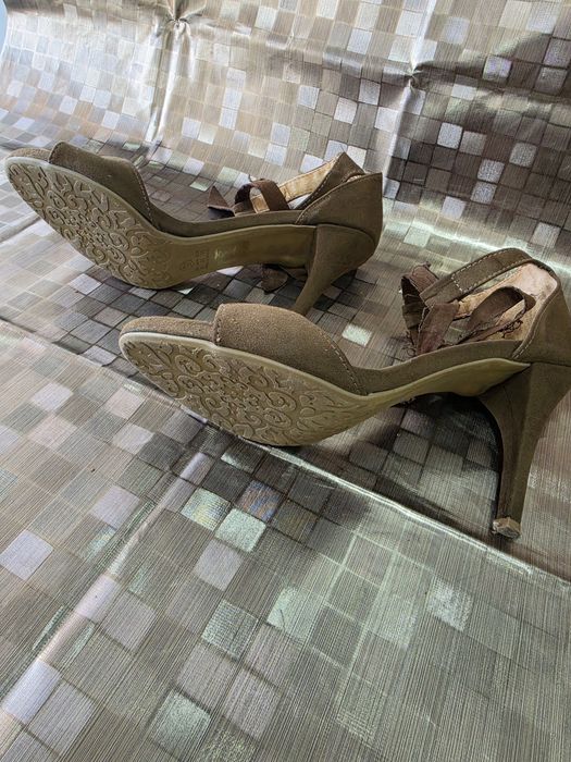 Sandálias de salto fino em camurça marrom, semelhantes aos modelos da Vizzano com amarração no tornozelo