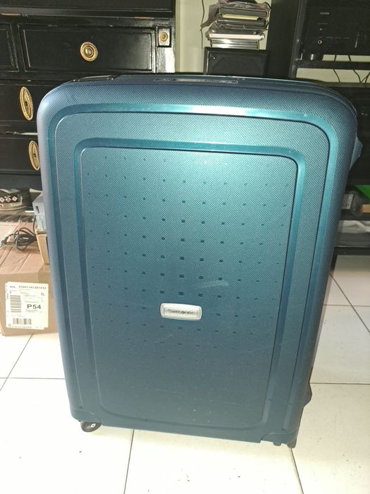 Vendo uma mala média da Samsonite S'Cure DLX Spinner em tom verde metálico com um design rígido de fecho de três pontos.