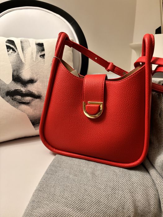 Mala nova, de cor vermelha, com alça à tiracolo.