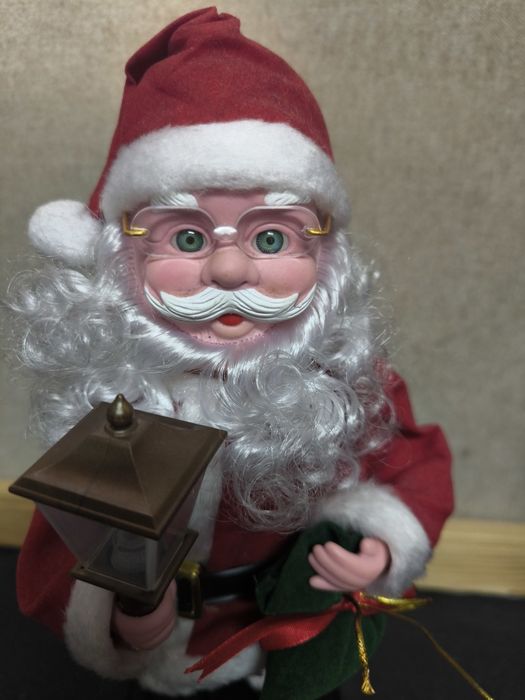 Pai Natal com candeeiro e saco de presentes com música.
Figura decorat