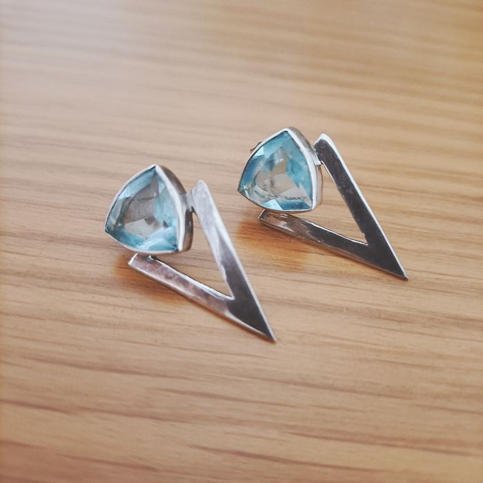 Brincos em prata com contraste e pedra azul.