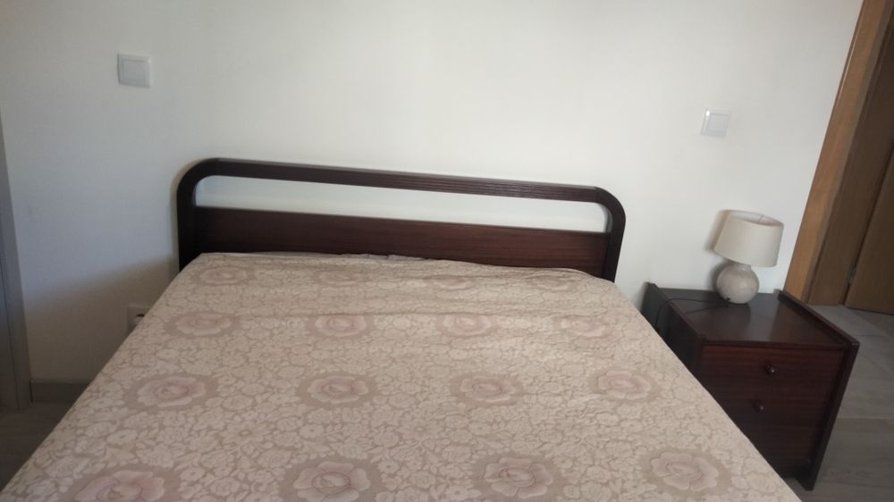 Cama de casal com colchão e uma mesa de cabeceira