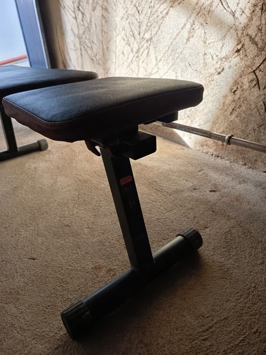 Anilhas, halteres, barras e banco de ginásio.