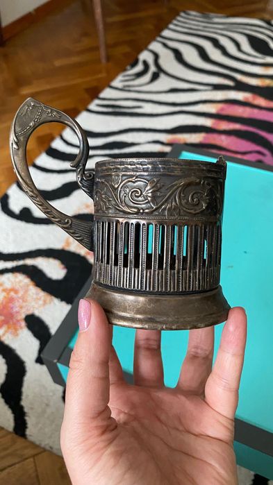 metalowy, posrebrzany uchwyt do szklanki, znany jako podstakannik.