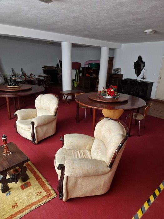 Duas poltronas clássicas para sala de estar, com estofado em tecido claro e estrutura em madeira escura.