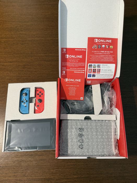 Vendo Nintendo Switch clássica com comandos Joy-Con azul e vermelho, em estado novo.