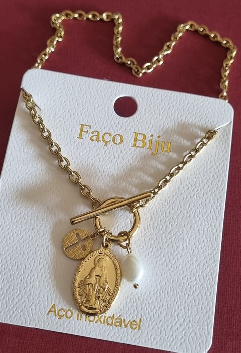 Colar dourado, em aço, com 3 pingentes diferentes. Fecho em T à frente