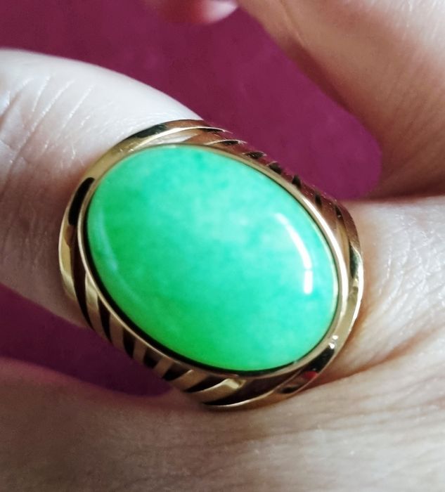Anel dourado, em aço, com pedra oval verde claro. 18/ajustável