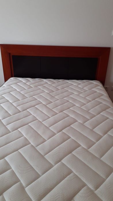 Cama de casal com uma mesa de cabeceira e colchão incluído