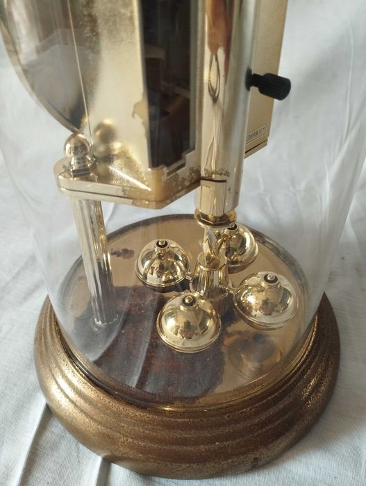 Relógio vintage de mesa sob cúpula de vidro, está a funcionar