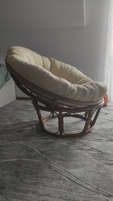 Duży fotel wiklinowy z poduszką.