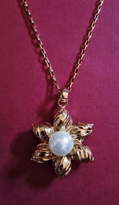 Colar dourado, em aço, flor com pérola. Tem extensor
