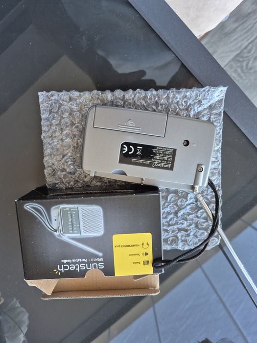 Rádio portátil analógico com tira de fixação e saída para auriculares.