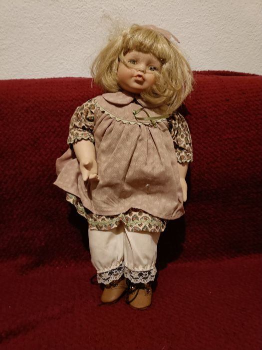 Boneca de porcelana com almofada de ursinho  dela