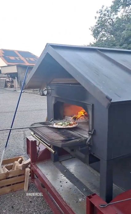 Forno de pedra a lenha profissional e móvel, montado sobre um chassis de reboque, concebido para eventos e utilização comercial em pequena escala.