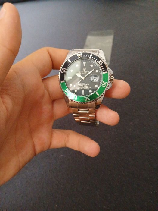 Rolex Submariner, z czarną tarczą i charakterystycznym zielonym bezelem.