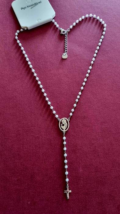 Colar prateado, em aço, em forma de terço com pequenas pérolas.