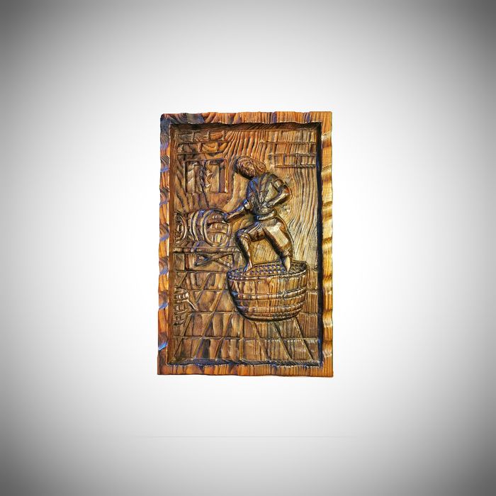 Drewniana płaskorzeźba - postać przy tradycyjnym depczeniu winogron