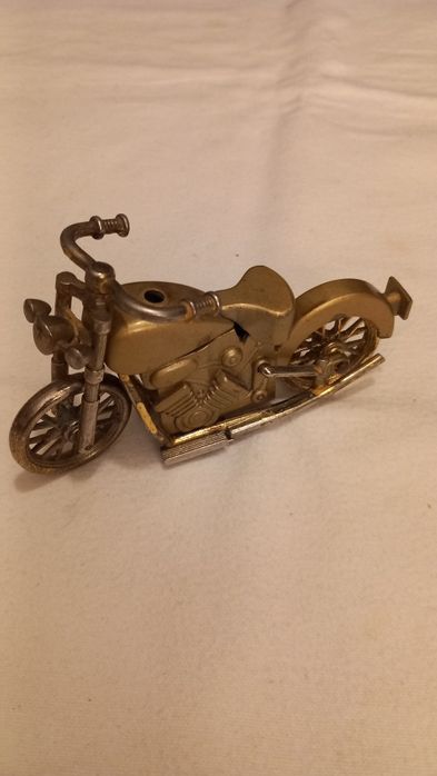 Isqueiro de mesa vintage em forma de motocicleta, frequentemente associado a modelos Harley Davidson.