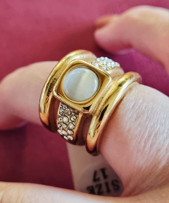 Anel dourado, em aço, com zirconias e uma pedra "olho de gato". T17