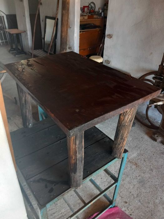 Mesa rústica de madeira maciça, antiga, tampo retangular espesso, pernas robustas em troncos roliços escurecidos