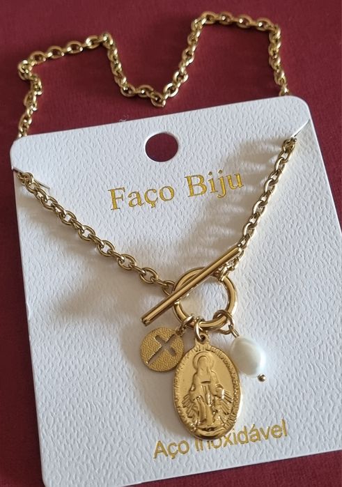 Colar dourado, em aço, com 3 pingentes diferentes. Fecho em T à frente