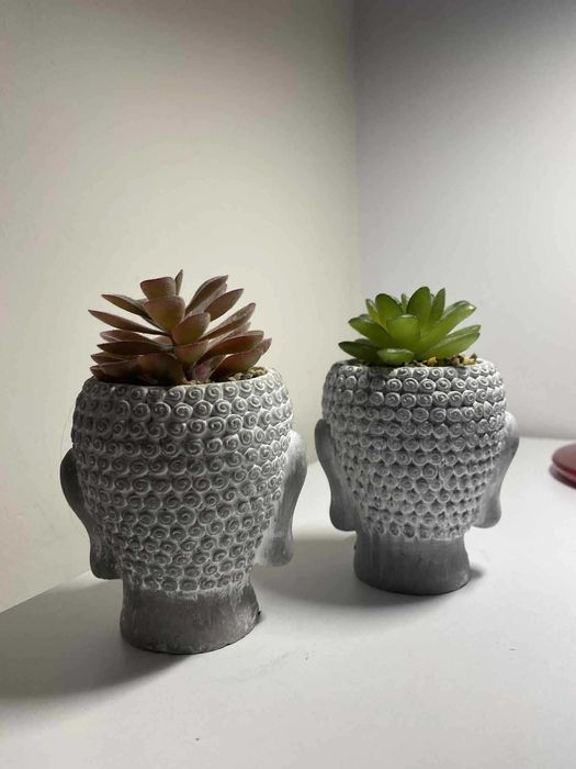 dwie figurki budda ze sztucznym kwiatkiem