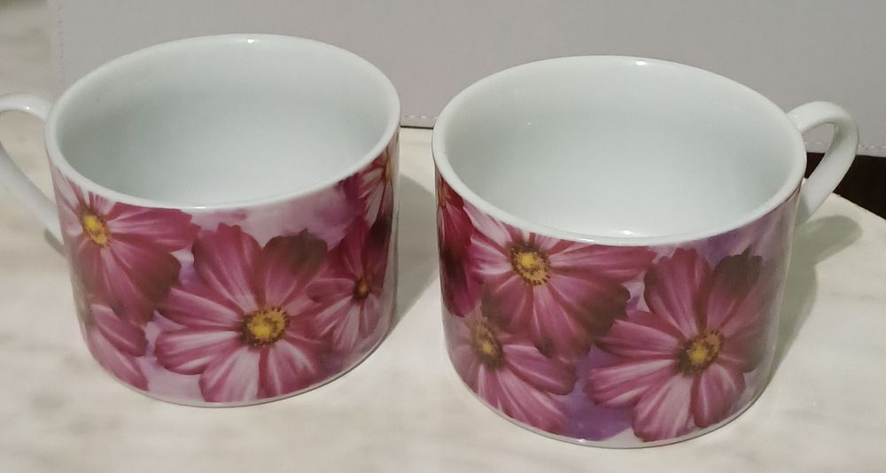 Две одинаковые белые кружки с цветочным принтом.
Кружки украшены крупн