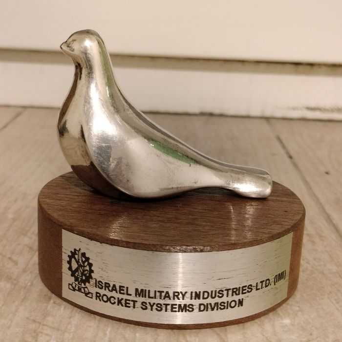 srebrna figurka ptaka (symbolu pokoju) na drewnianym stojaku