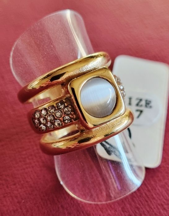 Anel dourado, em aço, com zirconias e uma pedra "olho de gato". T17