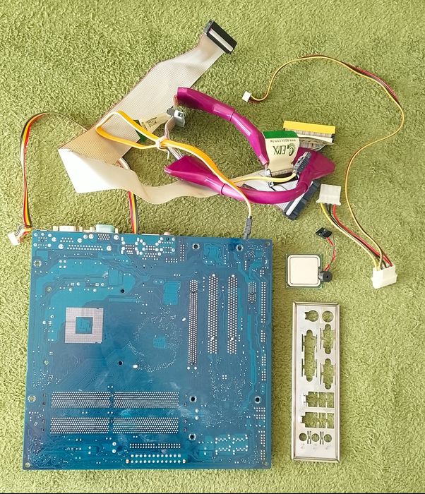 Płyta główna Gigabyte wraz z procesorem Intel Celeron głośniczkiem i kablami.