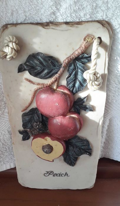 Placa em gesso, com palavra 'peach', com frutos e folhas verdes