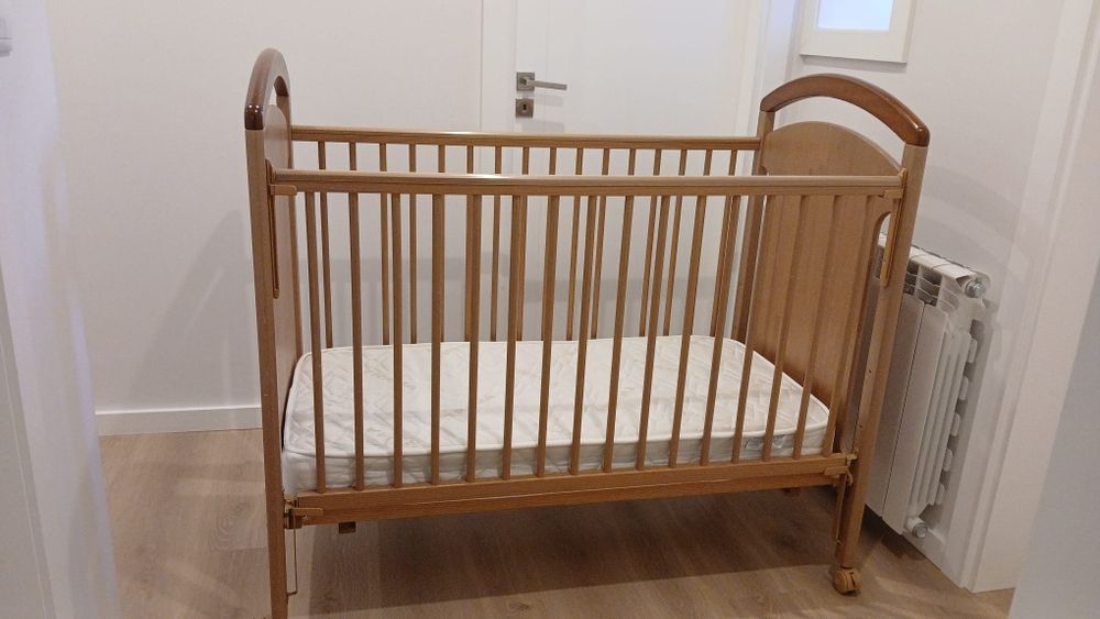 Cama de bebê, em madeira, cor bege.