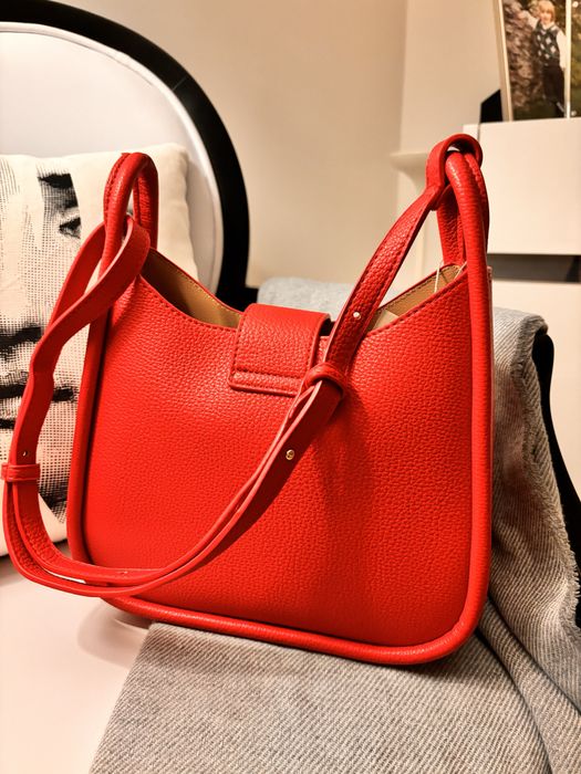 Mala nova, de cor vermelha, com alça à tiracolo.