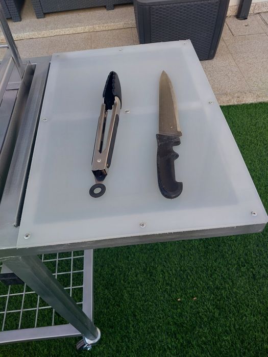 Churrasqueira com rodas, tem queimador  e grelha em inox  duas mesas de apoio uma em inox outra em nylon  e plataforma para lenha..