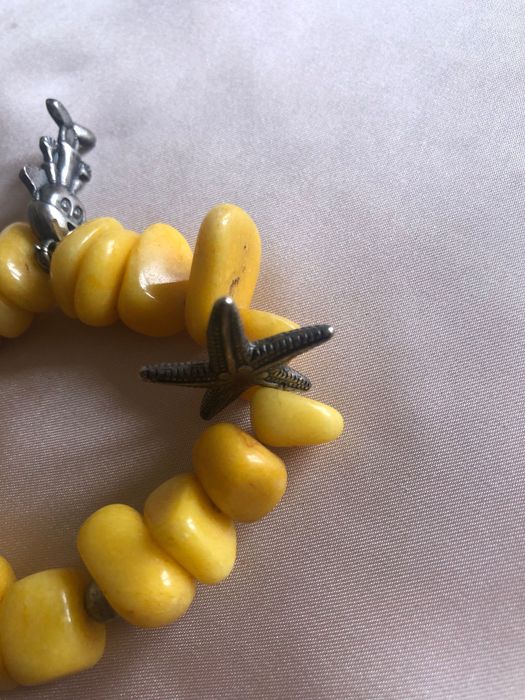 Pulseira com pedras amarelas e elementos metálicos como a estrela e outros