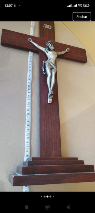 Crucifixo de mesa composto por uma cruz de madeira escura com uma base escalonada de vários níveis.A figura tridimensional do corpo de Cristo (corpus)