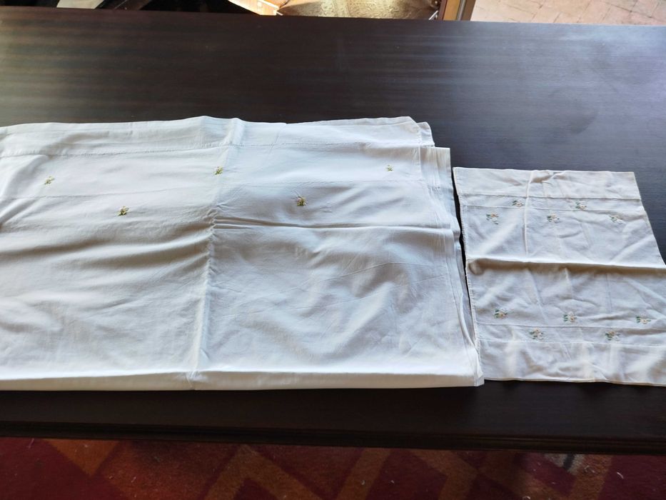 Lençol e almofada com flores bordadas a mão.