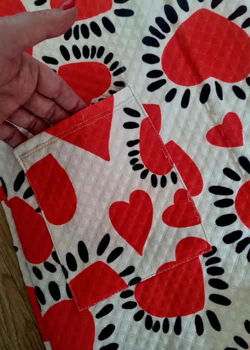 Casaco comprido com corações vermelhos em fundo branco.  TU